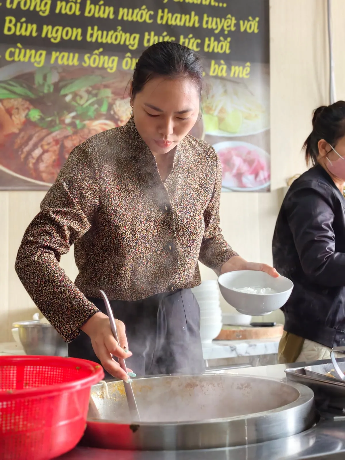 Cô Lam múc nước dùng tại bếp Quán Lam