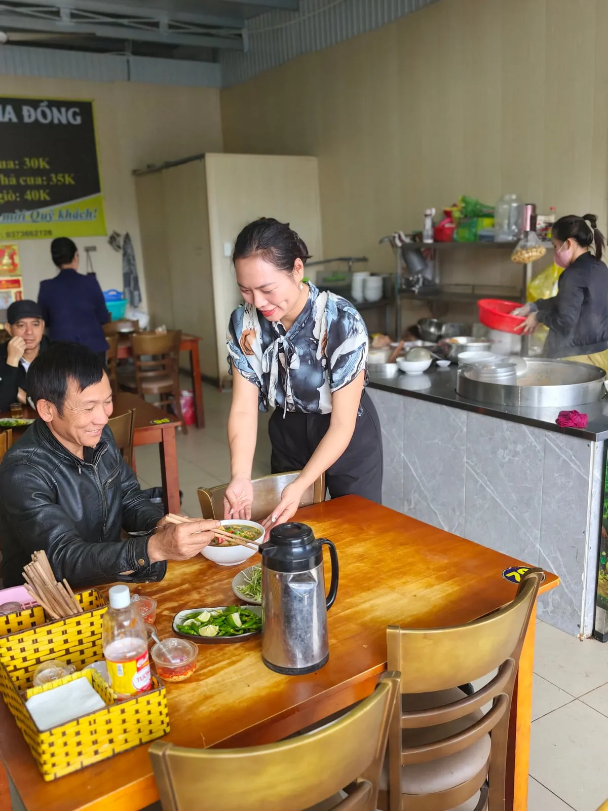 Cô Lam mang tô bún ra bàn cho khách tại Quán Lam